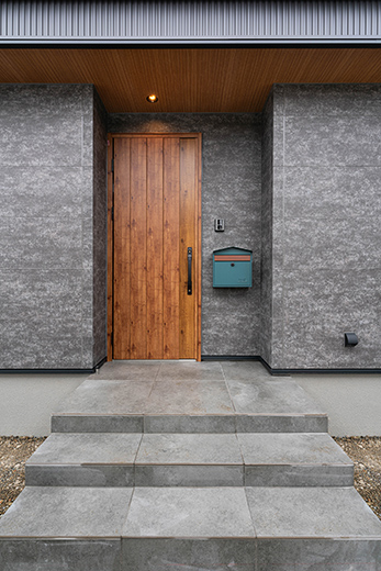洗練されたダークグレーのファサード。レトロカラーの家型のポストが玄関に彩りをプラス