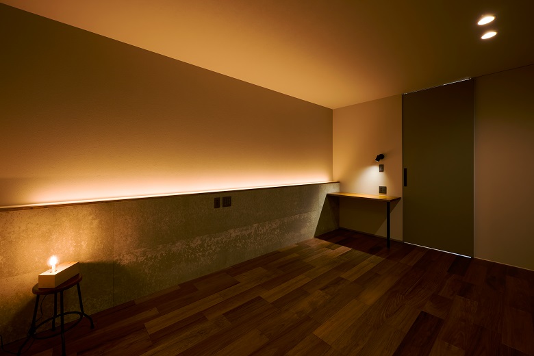 寝室は柔らかい間接照明の光で癒しの空間に。壁材にKMEWの内装材、SOLIDO、コーヒー豆の材料を使い、消臭効果も