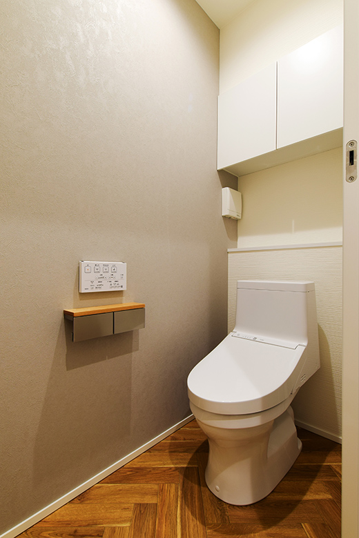 シンプルで落ち着いたデザインのトイレスペース。ヘリンボーンのフローリングが空間に温かみを加え、上質な雰囲気を