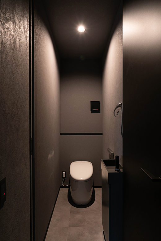 ダークトーンでまとめたシックなトイレ空間。壁や床のグレーの質感が高級感を引き立てる