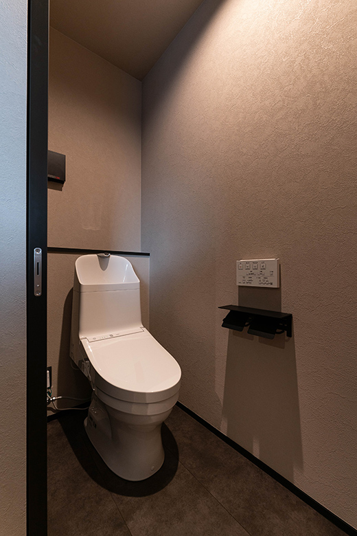 壁と床のテクスチャが温かみを与え、ナチュラルなトーンでまとめたトイレ空間