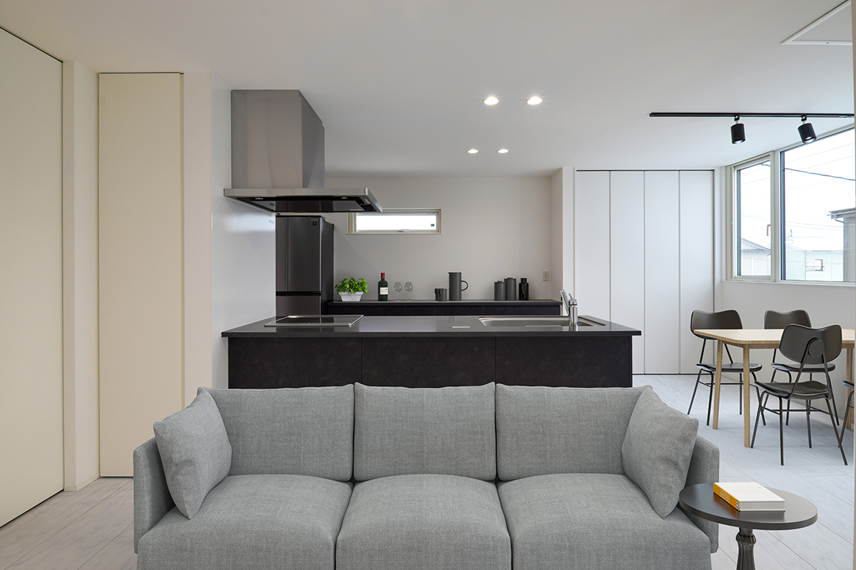 LDKがゆるやかにつながるL字構成。中心となるスタイリッシュな黒のキッチンは、白で統一された空間の中でひときわ存在感を放つ