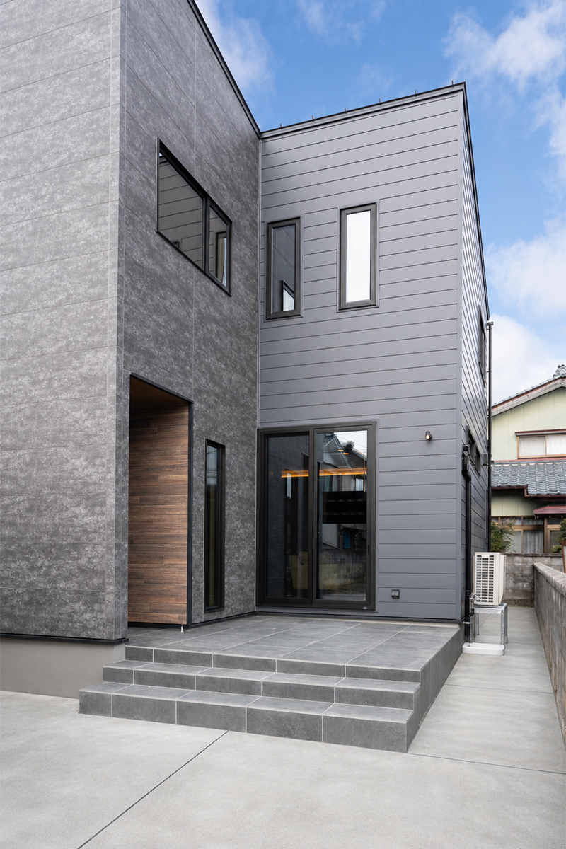 ポーチとテラスが一体となり、コンパクトな住まいでもアウトドアを楽しめる場所を計画。 素材の切り替えが奥行きを生み、心地よい居場所を作る