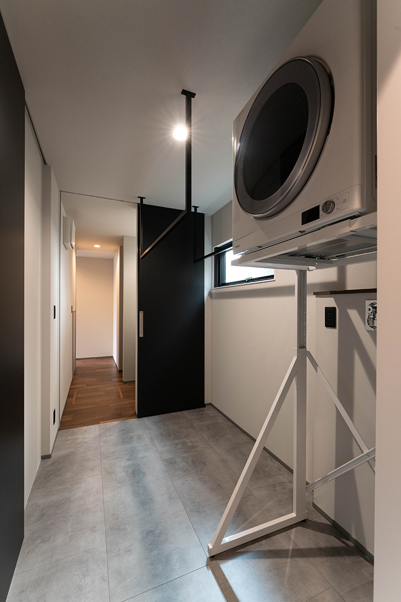 汚れが落ちやすいモルタル調フローリングをランドリー床に。奥に続く洗面、トイレのある廊下を抜け、角を曲がると玄関に行ける回遊動線を採用