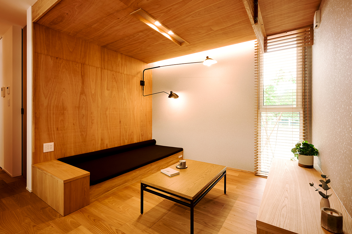 木に包まれるような安心感のある造作ソファ空間。間接照明と縦長の窓から差し込む自然光が、穏やかなひとときを演出