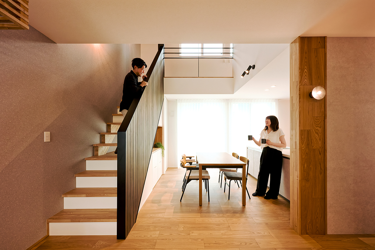 吹き抜けから降り注ぐ光が、ダイニングに心地よい開放感をもたらす空間設計。家族の会話が自然と弾む、のびやかな食卓の風景に