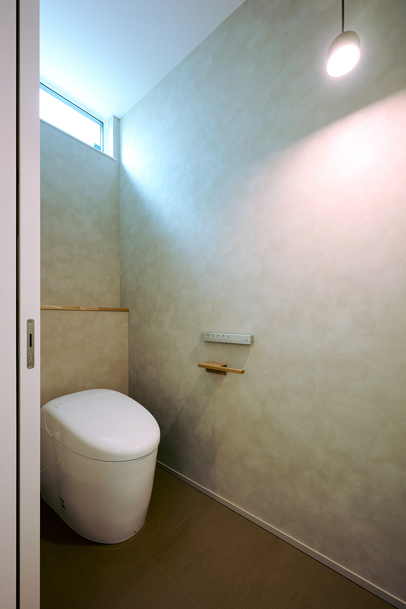 質感あるグレージュの壁とペンダントライトが印象的なトイレ空間。上質な静けさを感じるプライベートスペースに