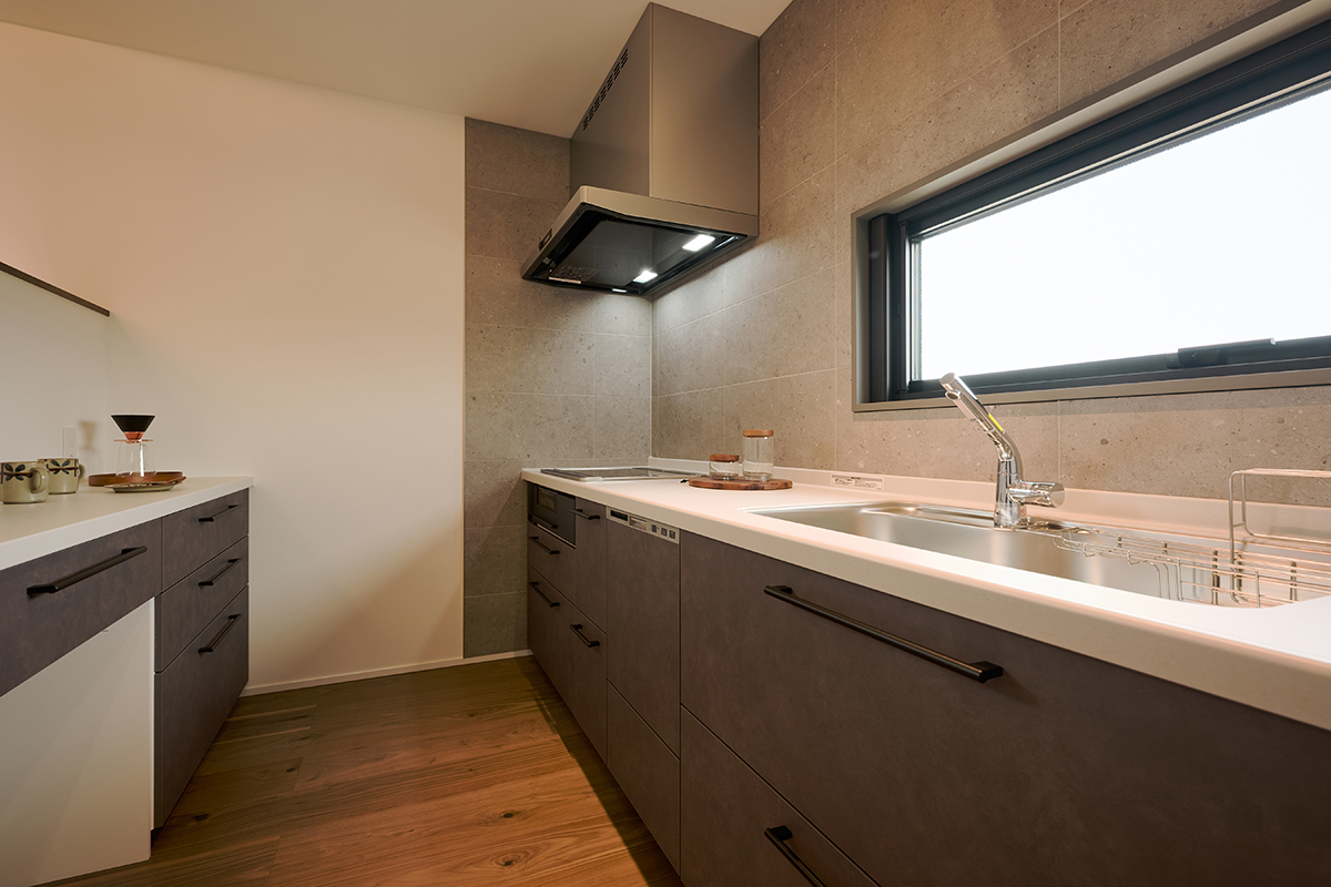 石目調の壁面とマットな扉材が調和し、上質な印象を生むキッチン。手元が明るく、作業のしやすさにもこだわった