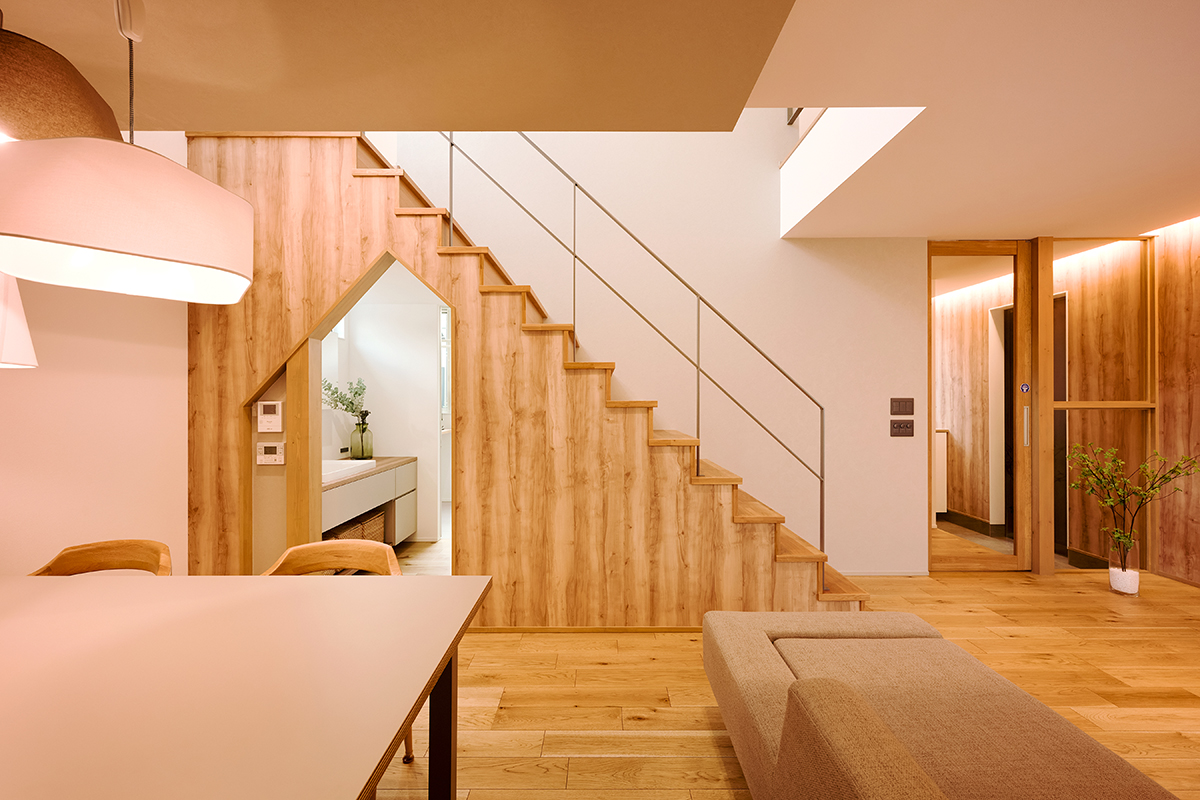 階段下のスペースを活用して見た目にも楽しい三角形の開口を設けた。奥には洗面室やトイレ、浴室などの水回り動線を集約