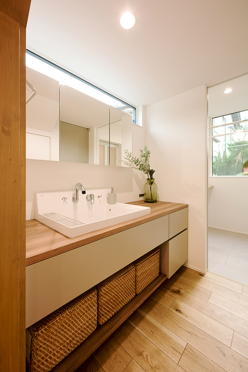 洗面室は南に面した幅の広い高窓のおかげで階段下とは思えない明るさ。天板に木を使い、リビングなどと同様にナチュラル感のあるコーディネート