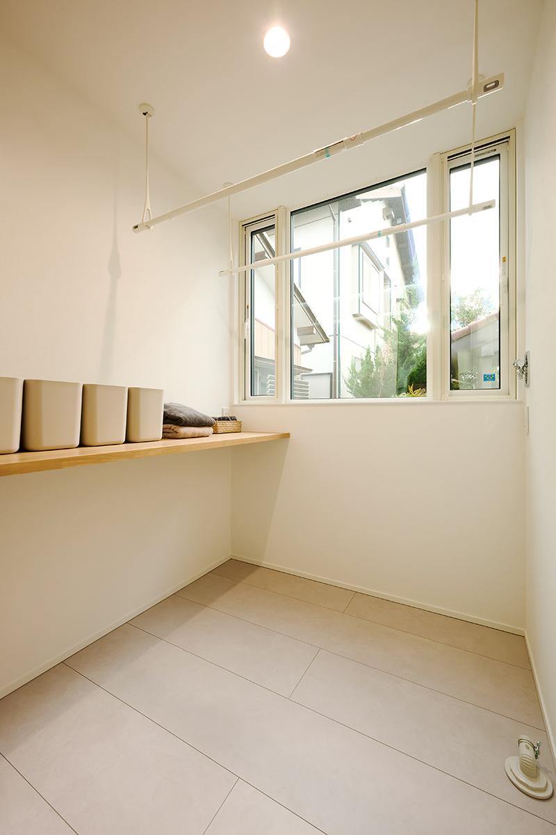脱衣室兼ランドリールームは物干し金物を二列備え、大きな窓で採光･通風を確保。造作カウンターもあるのでアイロンがけや畳む作業までここで完結できる