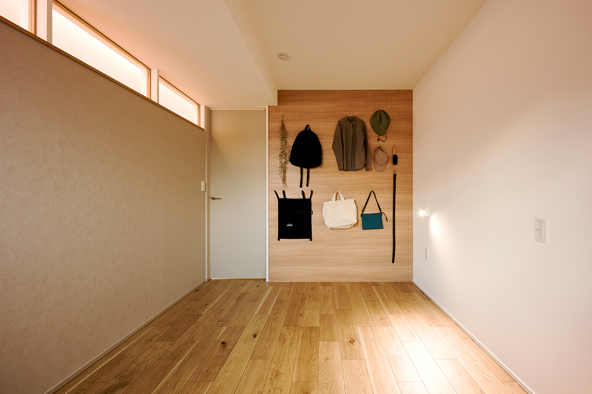 寝室は室内窓を通じて吹抜けからの明かりを取り込める。壁一面に有孔ボードを備え、雑貨や帽子、バッグなどをおしゃれにディスプレイできる